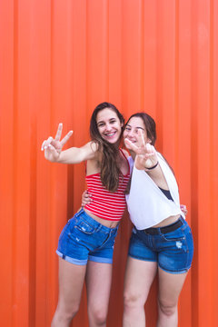 Two happy cheerful teenage girls in showing peace gesture
