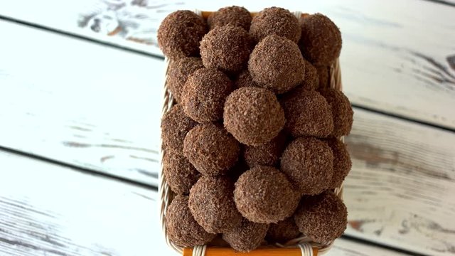 Chocolate ball-shaped cookies in basket. Delicious truffles with biscuit crumbs on wooden background. Tasty homemade pastry.