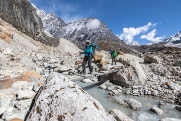 Woman trekker crosses a log bridge in the Hinku Valley