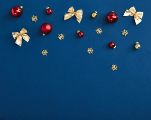 Red ball and golden bow on classci blue background. Horizontal composition, flat lay, top view. Merry christmas color greeting card template with copy space. Trendy 2020 classic blue background