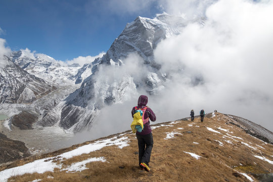 A woman descends a gentle ridge into the fog, Himalayan peaks in back