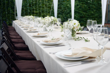 Table setting with sparkling wineglasses and cutlery in tent outdoors, copy space. Place setting at wedding reception. Table served for wedding banquet in restaurant