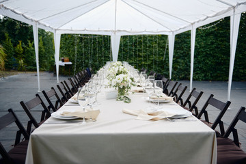 Table setting with sparkling wineglasses and cutlery in tent outdoors, copy space. Place setting at wedding reception. Table served for wedding banquet in restaurant
