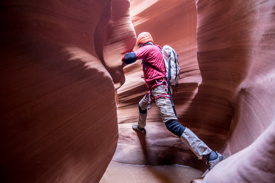 A canyoneer take a big step to avoid deep pothole in slot canyon