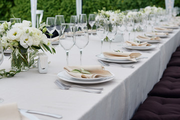 Table setting with sparkling wineglasses and cutlery in tent outdoors, copy space. Place setting at wedding reception. Table served for wedding banquet in restaurant