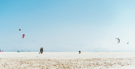 Obraz premium beach view, away people flying kites, sand, ocean and blue sky