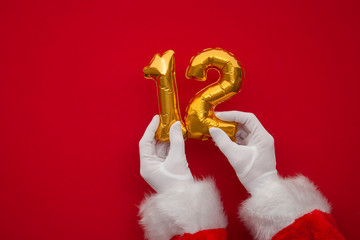 12 days of christmas. Santa hands holding 12th day balloon on red background