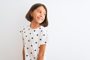 Young beautiful child girl wearing casual t-shirt standing over isolated white background looking...