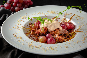 Grilled duck or turkey poultry fillet with berry sauce with baked grapes and caramelized onions. Restaurant menu. Background black boards.