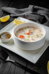 Cream soup of salmon, shrimp and vegetables. Restaurant menu. Background black boards.