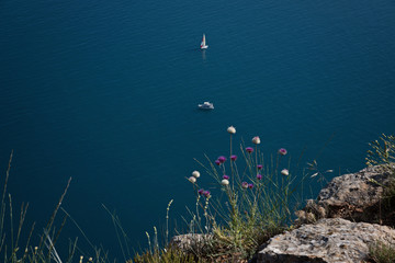 Blue sea surface with yachts and cliff mountains, rocks and grass. Landscape. Classic Blue color 2020.
