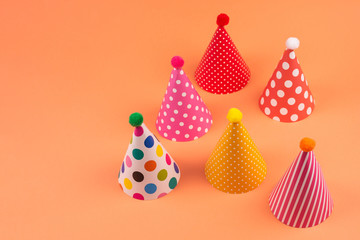 Colorful birthday caps on orange background.