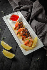Grilled crispy prawns with lemon and sauce. Restaurant menu. Background black boards.