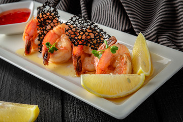 Grilled crispy prawns with lemon and sauce. Restaurant menu. Background black boards.