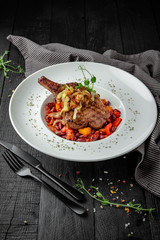 Bone steak in vegetable stew. Beef or pork shoulder, rib. Restaurant menu. Background black boards.