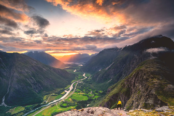 Elevated view of man standing on Romsdalseggen ridge admiring Rauma valley during sunset, Andalsnes, More og Romsdal
