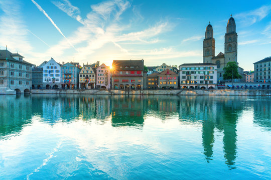 Limmatquai and Grossmunster Cathedral mirrored in Limmat River at dawn, Zurich