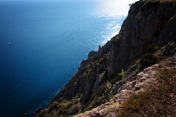 Blue sea surface with yachts, mountains, rocks and grass on the cliff. Landscape. Classic Blue color 2020.