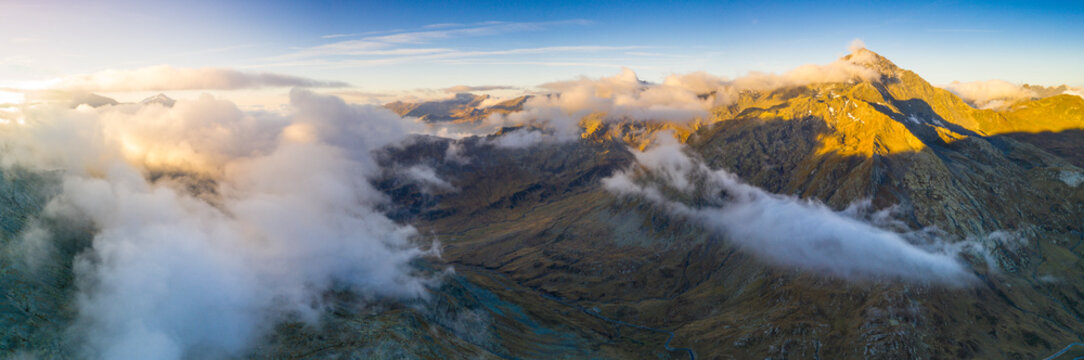 Aerial panoramic of sea of clouds over Pizzo Tambo and bends of the Spluga Pass road, Valle Spluga, Valtellina, Lombardy