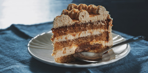 Slice of layered honey cake in a plate on wooden table