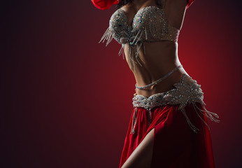 Beautiful belly dance of a girl in red decorated ethnic dress in the dark