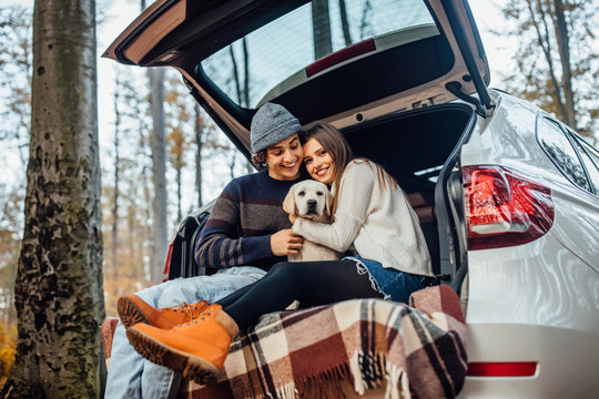 Young couple have a weekend time with their labrador retriver sitting in automobile in the autumn forest.
