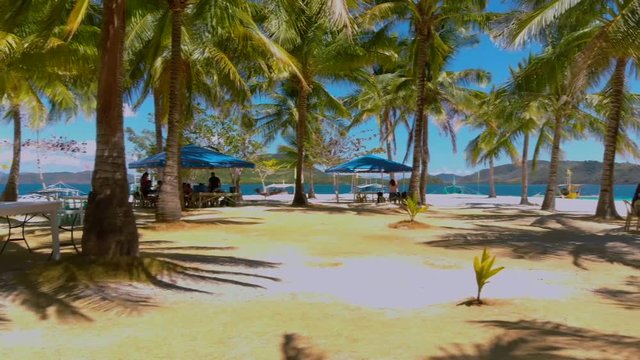 White sand beach and tropical island surrounded by palm trees at Punta Sebaring, Bugsuk Island in Balabac, Philippines