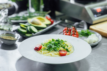 Professional pasta carbonara on a  worktop with vegetables, food ingredients and utensils.