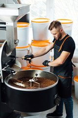 A worker near coffee roasting equipment will check time for testing the sample.