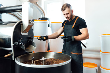 A worker near coffee roasting equipment will check time for testing the sample.