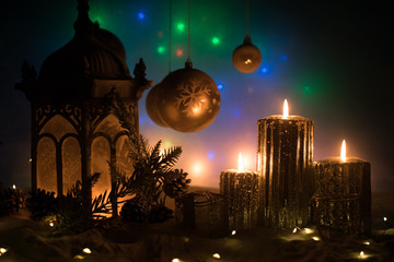 Creative artwork decoration. Christmas decoration with burning candles on a dark background. Christmas ornaments over dark golden background with lights.