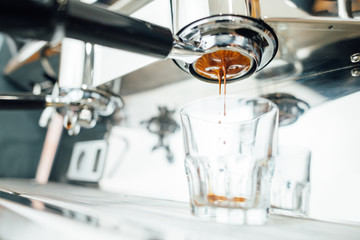 the middle of the espresso extraction process from bottomless portafilter in a glass cup,