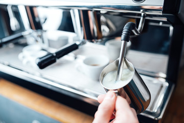 steam frothing milk under pressure from a coffee machine in pitcher