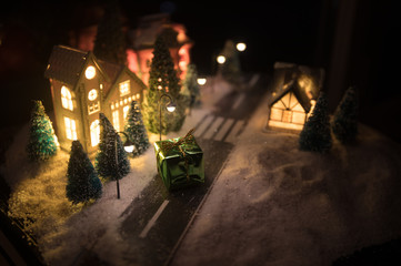 New Year miniature house in the snow at night with fir tree. Holiday concept. Selective focus