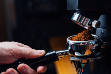 ground coffee pouring into a portafilter with a grinder - obrazy, fototapety, plakaty