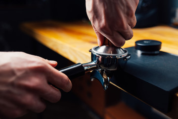 tempering coffee in portafilter on a dark background