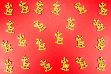 Background made of gold reindeer arranged randomly on a red background.