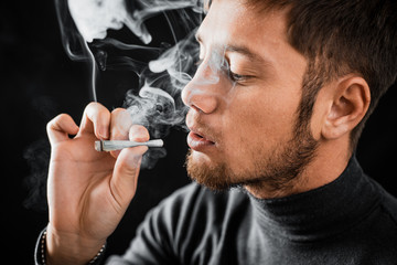 A man Smoking a cigarette rolled dollar in a tube, the concept of addiction, addiction and waste of money and money