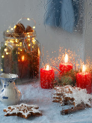 Christmas window. Candles, garlands, Christmas decoration, gingerbread cookie. Close-up, it is raining. Vertical orientation