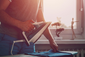 Man is ironing clothes. The concept of caring for the home, helping men in household chores. The...