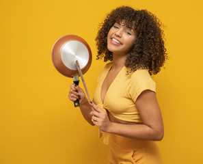 Cooking utensils. Cooking woman in kitchen with frying pan and wooden spoon. Housewife dancing.