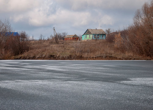 Landscape of winter village near frozen lake