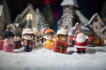 Christmas and New Year holidays concept. Little decorative cute small houses in snow at night in winter, Fir tree standing on snow with beautiful holiday decorated background