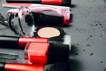 A set of cosmetics on a dark stone background. The concept of doing makeup, caring for the appearance of women. Applying brushes, eye shadows, powder.