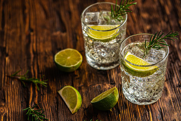 Gin and tonic with lime and ice on wooden table