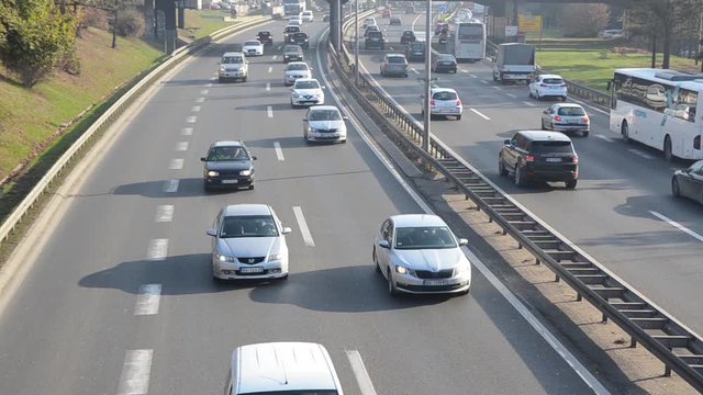 Cars driving through highway during rush hour in city. Automobile driving on freeway. Moving cars on streets in town. Air pollution. Traffic jam. Transportation. City traffic. 