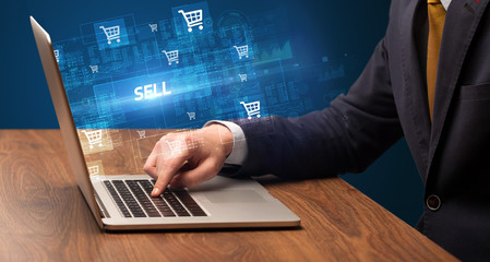 Businessman working on laptop with SELL inscription, online shopping concept