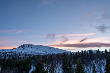 Snow covered mountain top in the wilderness with pink skies at night. Dusk and landscape concept. Copy space for text.