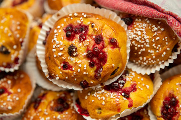 Homemade Saffron bun with lingonberries and pearl sugar on top and lying on a red checked towel in a basket