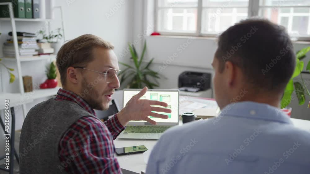 Wall mural panning shot of two web designers working on application interface for various devices. creative pro